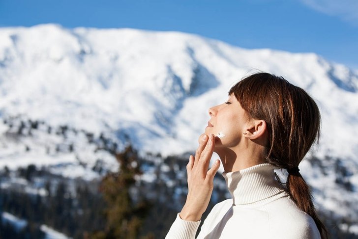 portrait of a beautiful woman in snow with application of the protective cream in winter