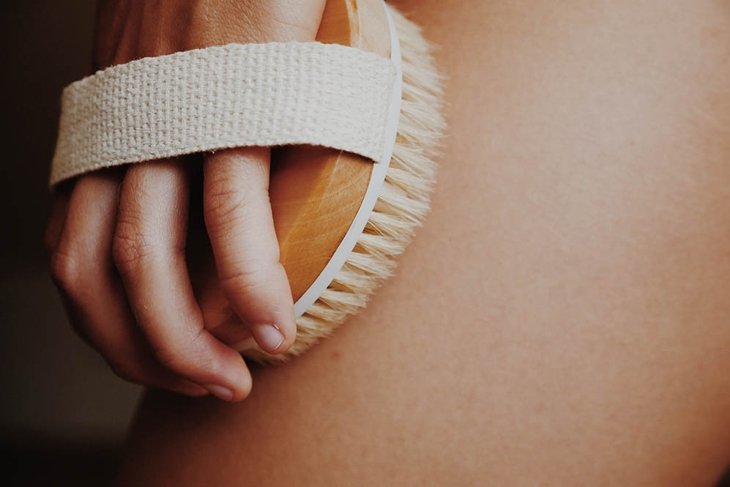 Woman\'s arm holding dry brush to top of her leg